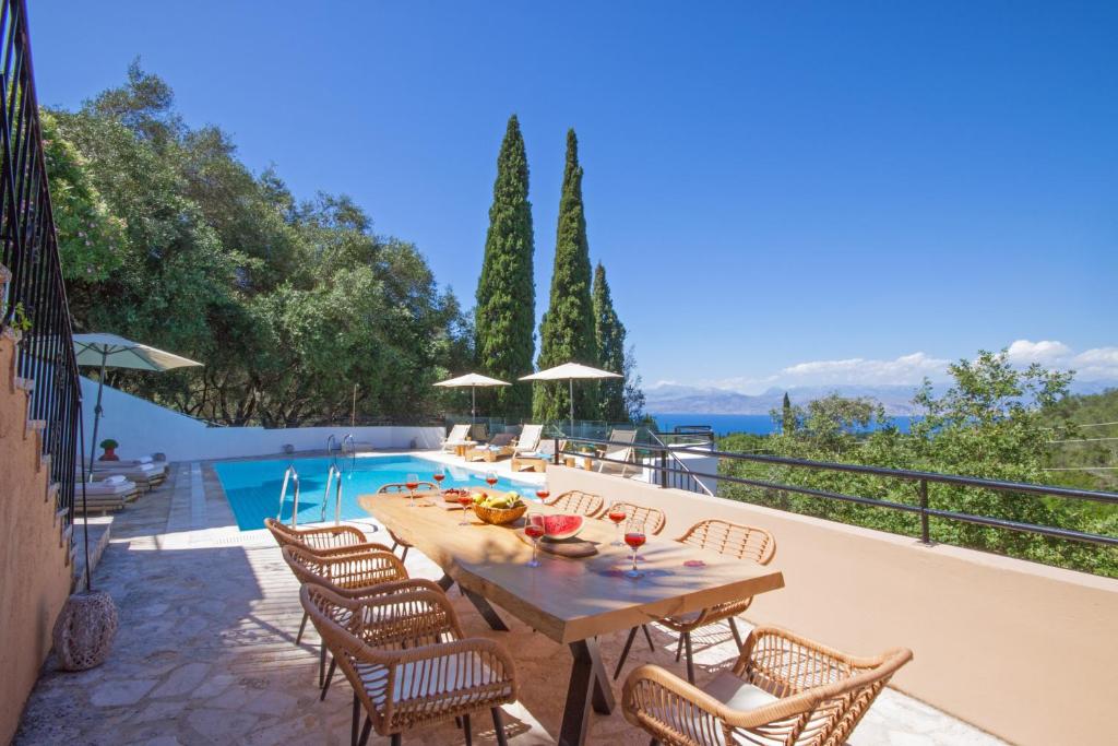 un patio con mesa y sillas junto a una piscina en Odyssey villas, en Kassiopi