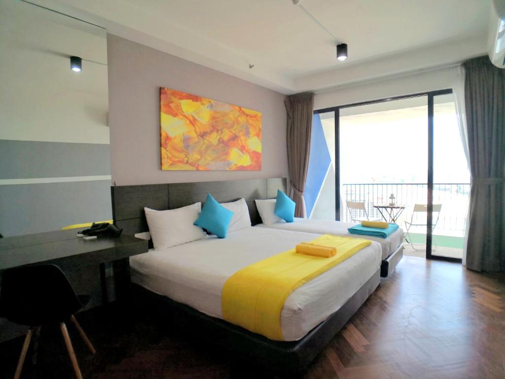 a bedroom with a large bed and a desk and window at The Landmark by Comfy in George Town