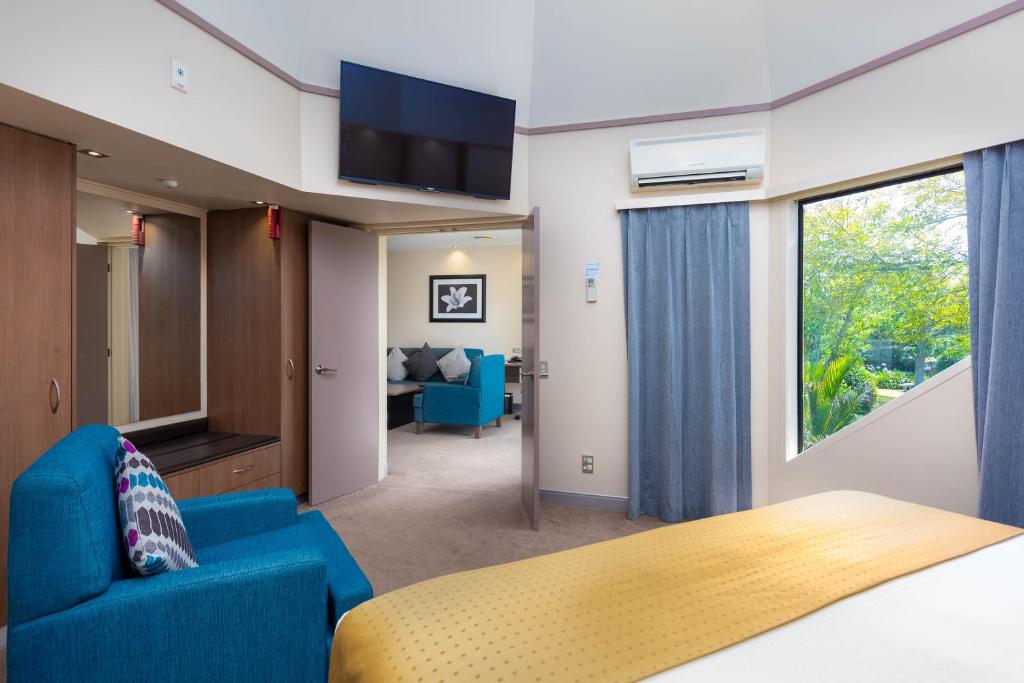 a bedroom with a bed and a couch and a tv at Holiday Inn Auckland Airport by IHG in Auckland