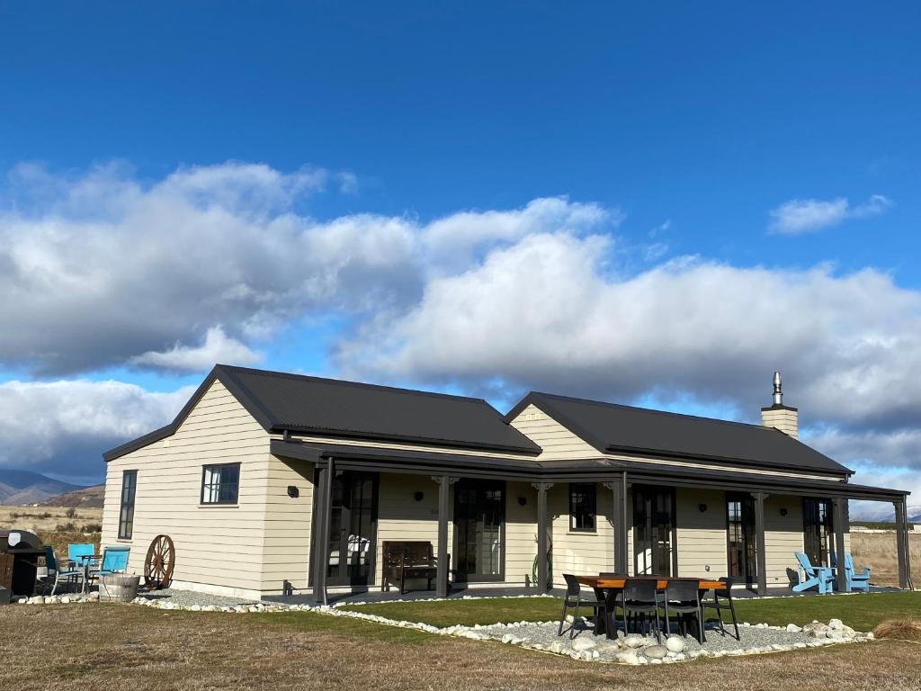 a large white house with a black roof at Pedalfish Cottages - Galaxy Views in Twizel