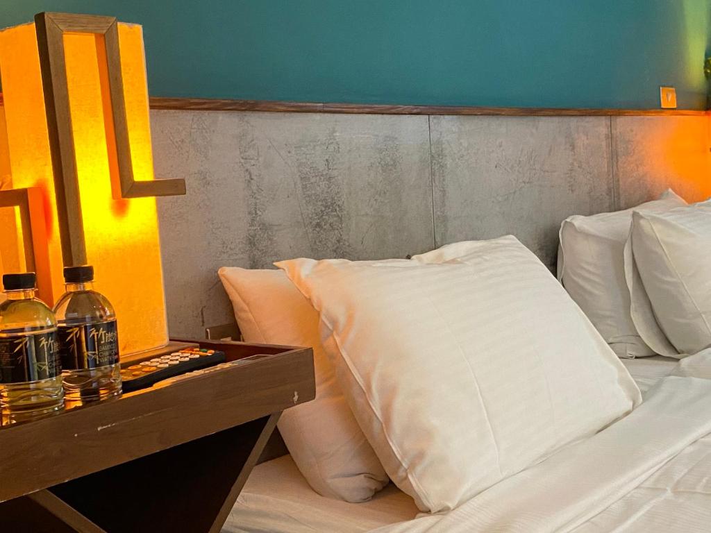 a bed with white pillows sitting next to a night stand at Playful House in Kenting
