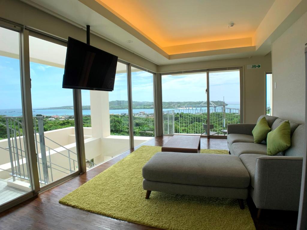 ein Wohnzimmer mit Couch und Flachbildfernseher in der Unterkunft KEN KEN VILLA YUUMODORO in Motobu