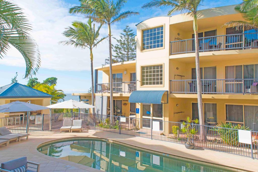 un complejo con piscina y palmeras en Beachside Holiday Apartments, en Port Macquarie