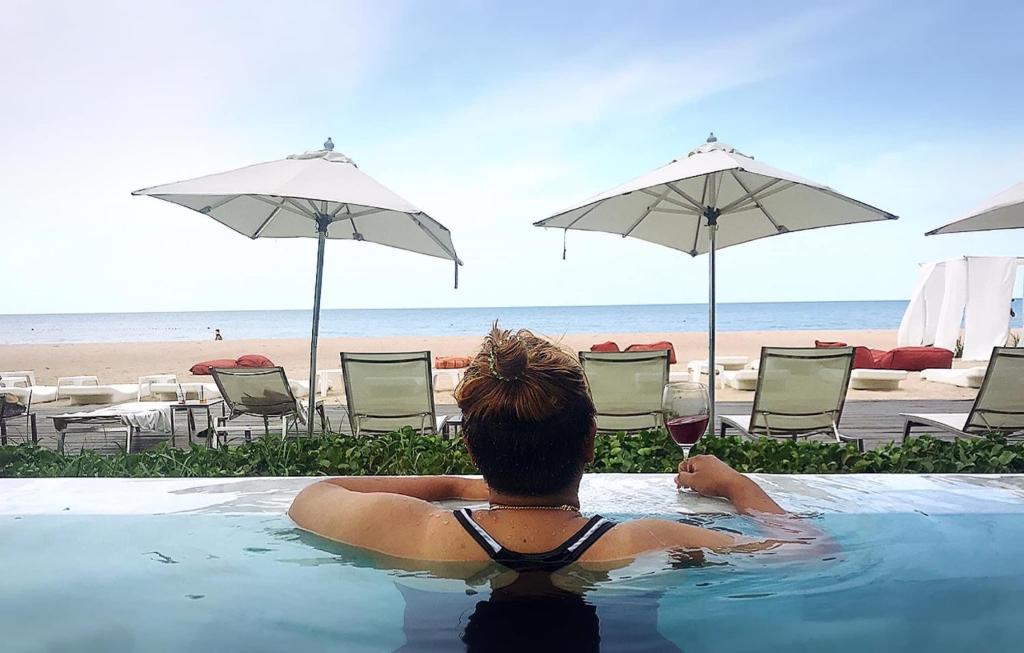 a person in a swimming pool with a glass of wine at Veranda Residence Pattaya by Nice in Na Jomtien