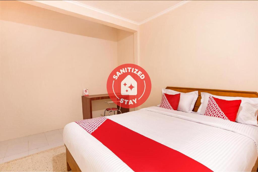 1 dormitorio con 1 cama con manta roja y blanca en OYO 3252 Lansano Residence Syariah, en Padang
