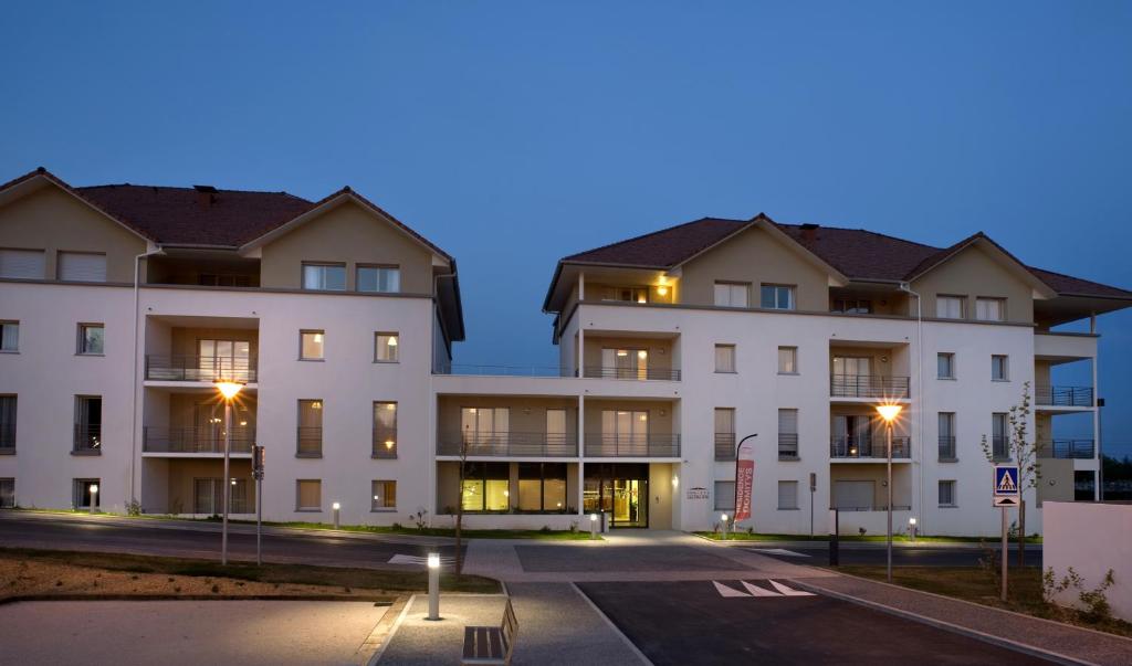 an empty parking lot in front of a building at Domitys Les Clés d'Or in Orthez