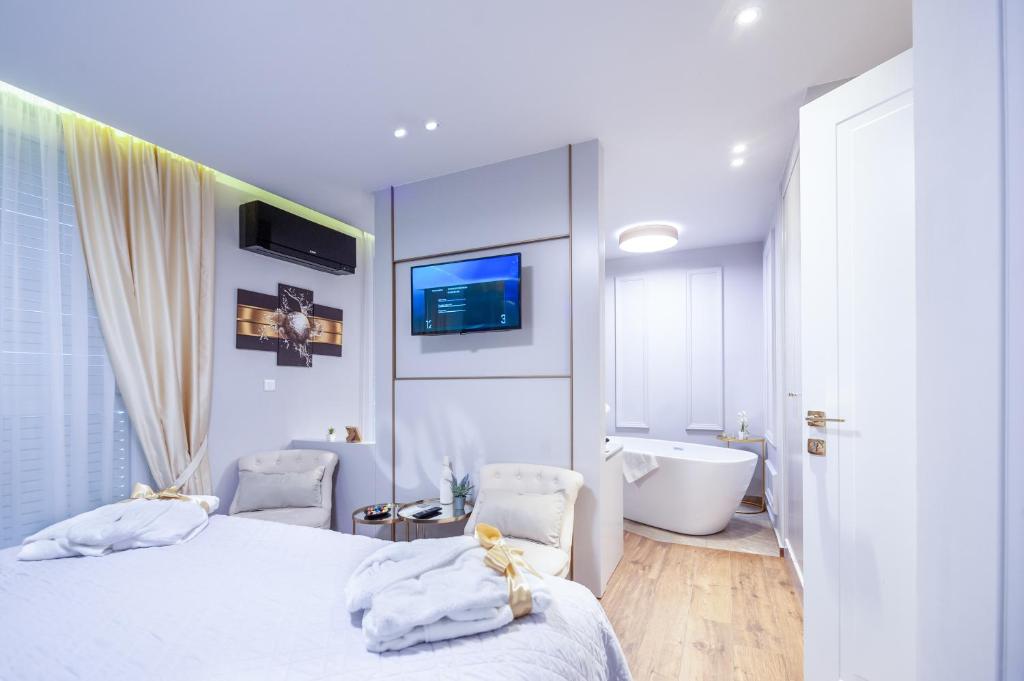 um quarto branco com uma banheira, uma cama e 2 cadeiras em Luxury rooms Kadena em Zadar