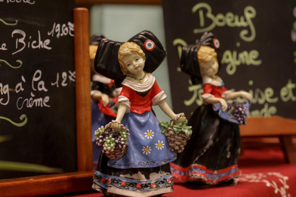 una figurita de dos chicas sosteniendo piñas en Hotel Restaurant 3 Châteaux, en Ribeauvillé