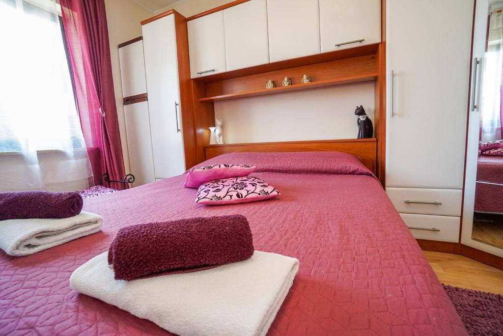 a bedroom with a pink bed with two pillows on it at Apartment Jasna in Umag