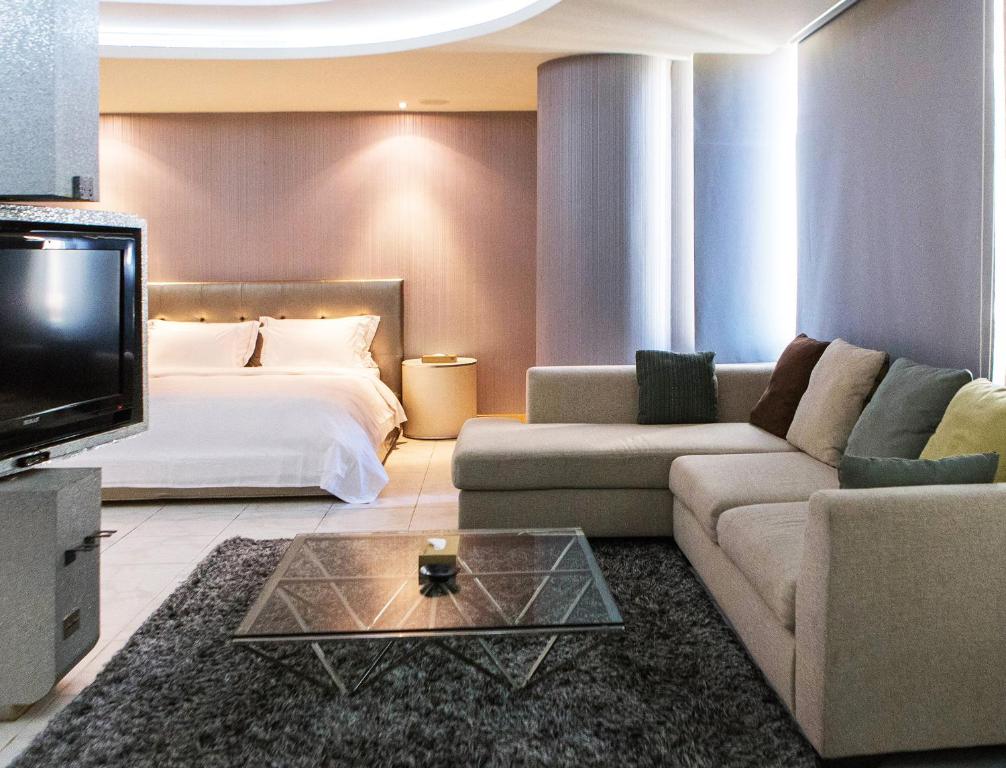 a hotel room with a bed and a couch and a tv at All-Ur Boutique Motel-Jhu Shan Branch in Zhushan