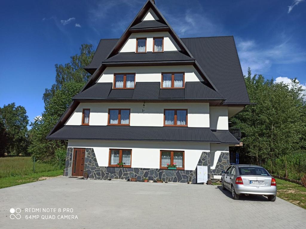 une maison avec un toit en gambrel et une voiture garée devant dans l'établissement Helena Gał, à Białka Tatrzańska
