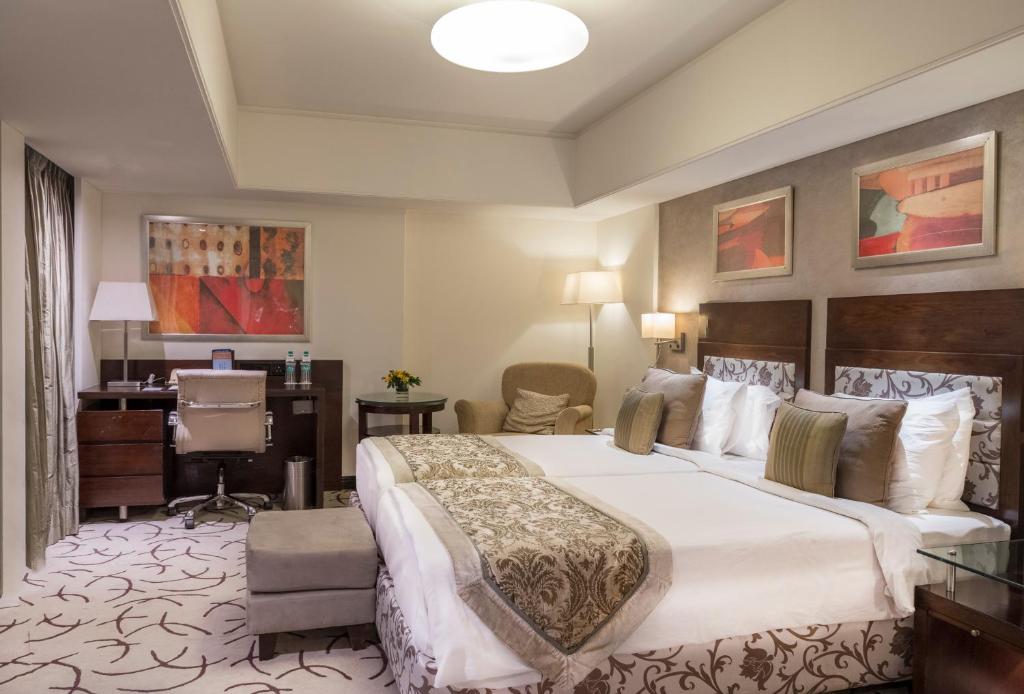 a hotel room with a large bed and a desk at Fortune Park Ahmedabad in Ahmedabad