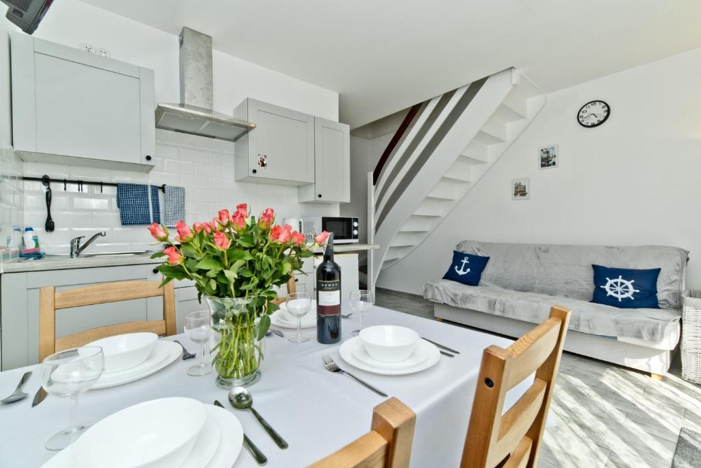 a kitchen and living room with a table with flowers at Apartamenty In Chałupy Kaperska in Chałupy