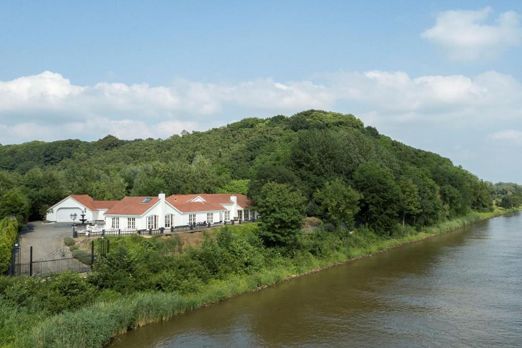 een huis op een heuvel naast een rivier bij Bed & Breakfast Trouwborst in Rhenen