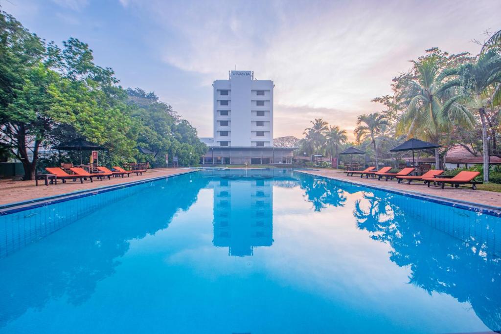a swimming pool with chairs and a building in the background at Vivanta Colombo, Airport Garden in Negombo