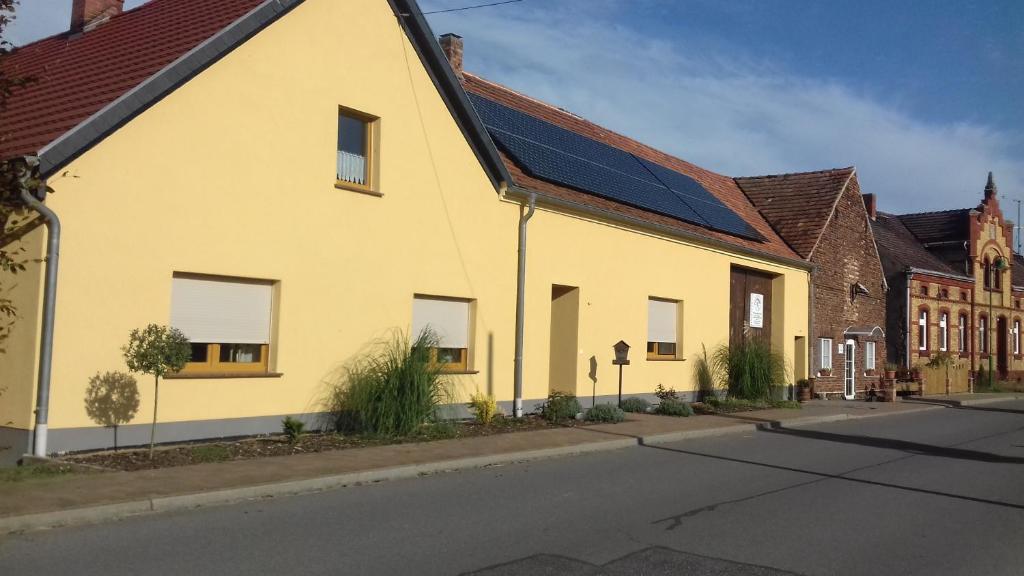 a yellow building with solar panels on it on a street at Ferienwohnung Wildau-Wentdorf in Drahnsdorf