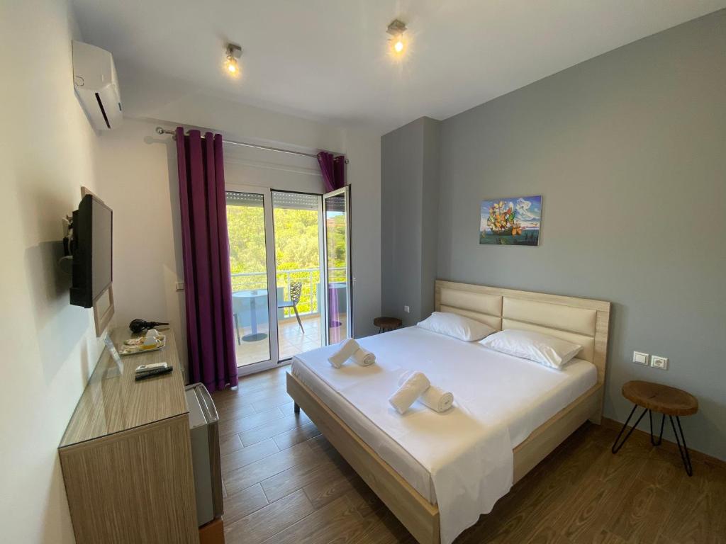 sypialnia z łóżkiem i telewizorem oraz balkonem w obiekcie VIAL Rooms w mieście Himara