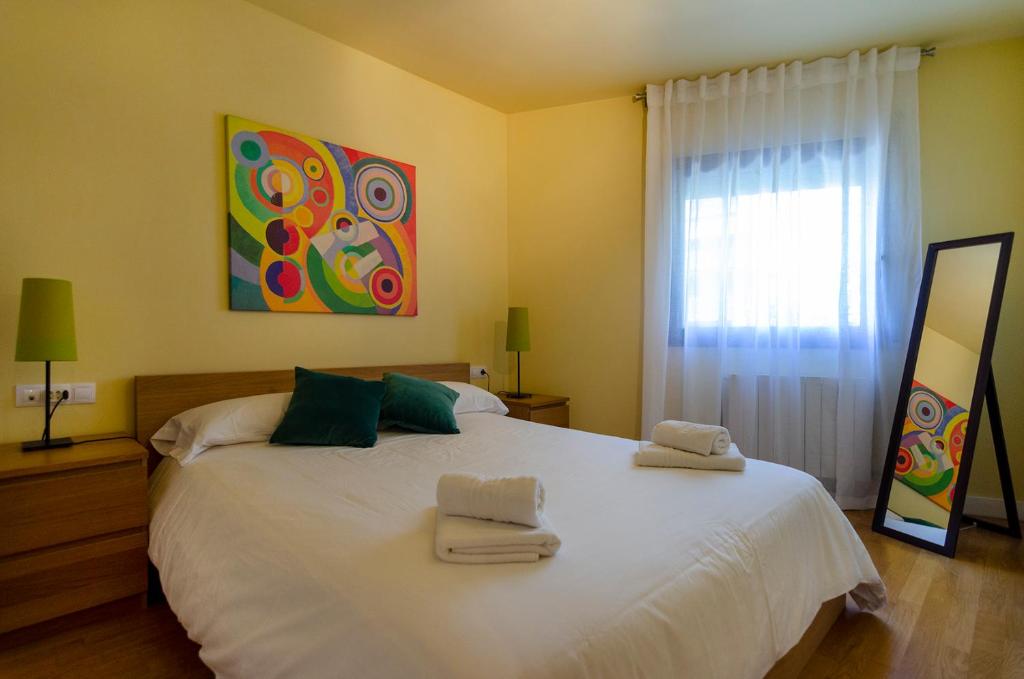 una camera da letto con un grande letto bianco con asciugamani di Devesa Park Apartment with Private Parking a Girona