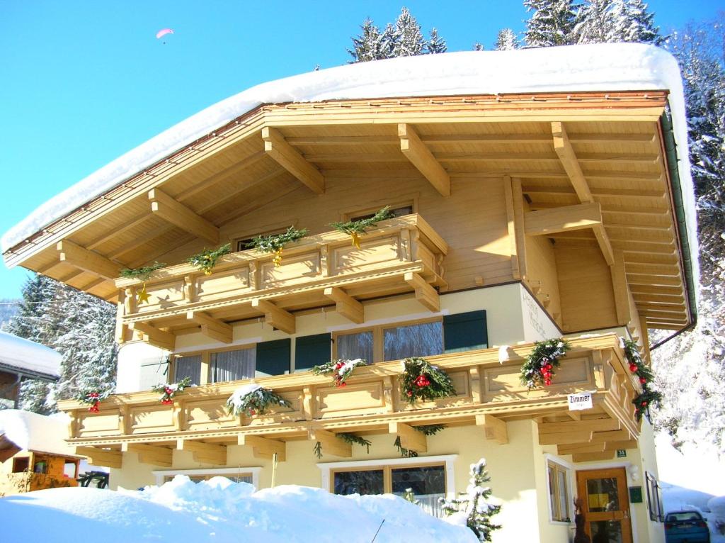 ein Gebäude mit einem Balkon mit Weihnachtspflanzen darauf in der Unterkunft Pension Mirabelle in Ellmau