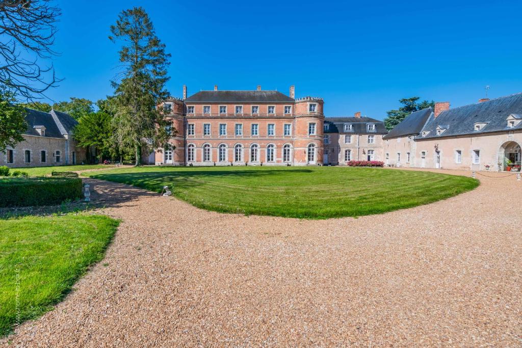 un gran edificio con un patio de césped delante de él en Château De Denonville, en Denonville