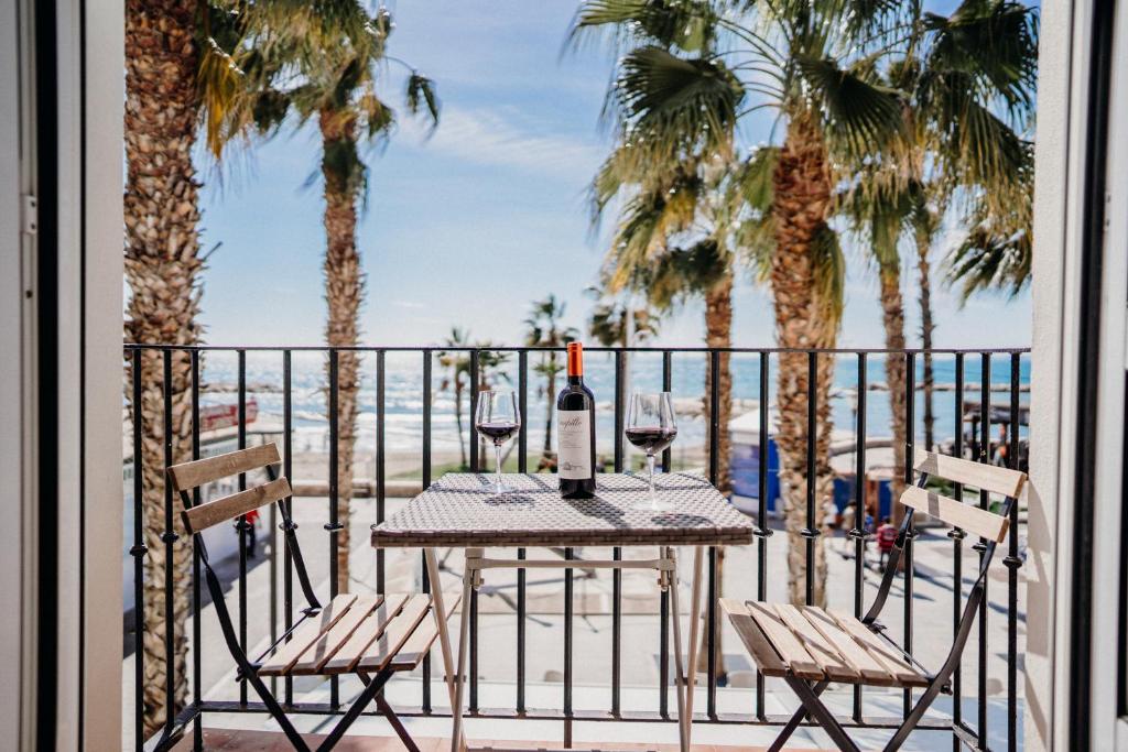 a table with wine glasses on a balcony with palm trees at MalagadeVacaciones - El Pedregal in M&aacute;laga