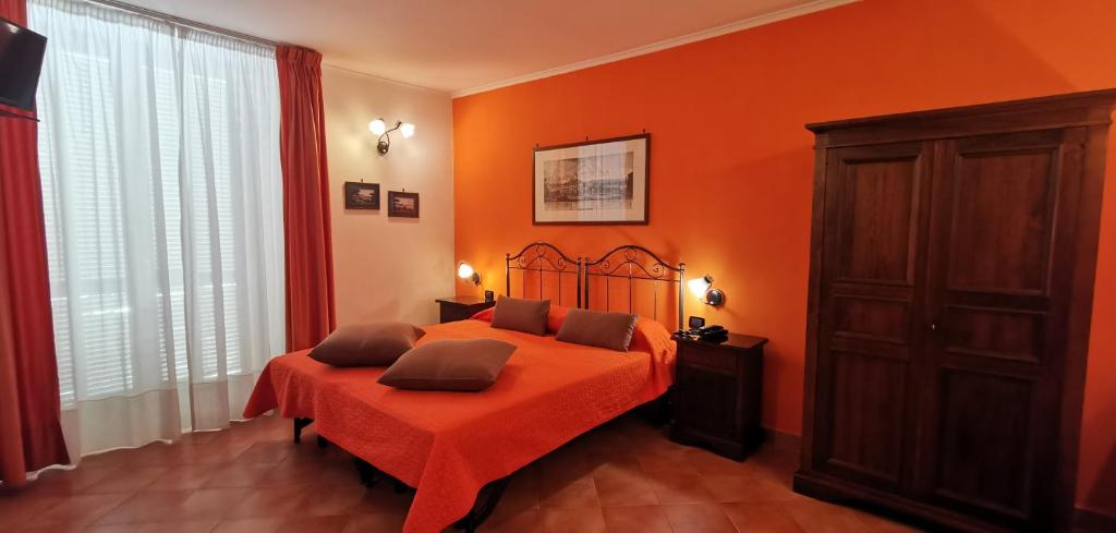 a bedroom with a bed with an orange wall at Hotel Neapolis in Naples