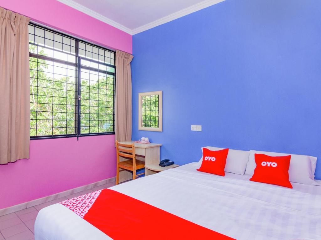 Un dormitorio con paredes coloridas y una cama con almohadas rojas. en Super OYO 1159 Hotel New Sabah, en Kota Kinabalu