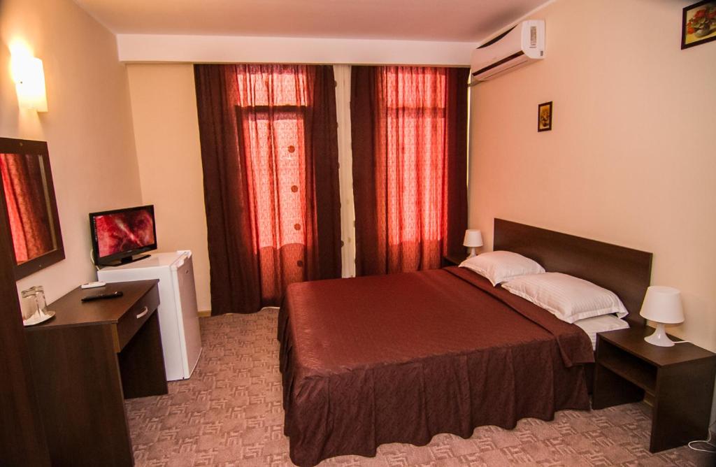 1 dormitorio con 1 cama y 2 ventanas con cortinas rojas en Vila KM 0, en Neptun