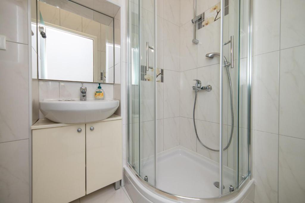 a white bathroom with a sink and a shower at Apartment Riva in Makarska