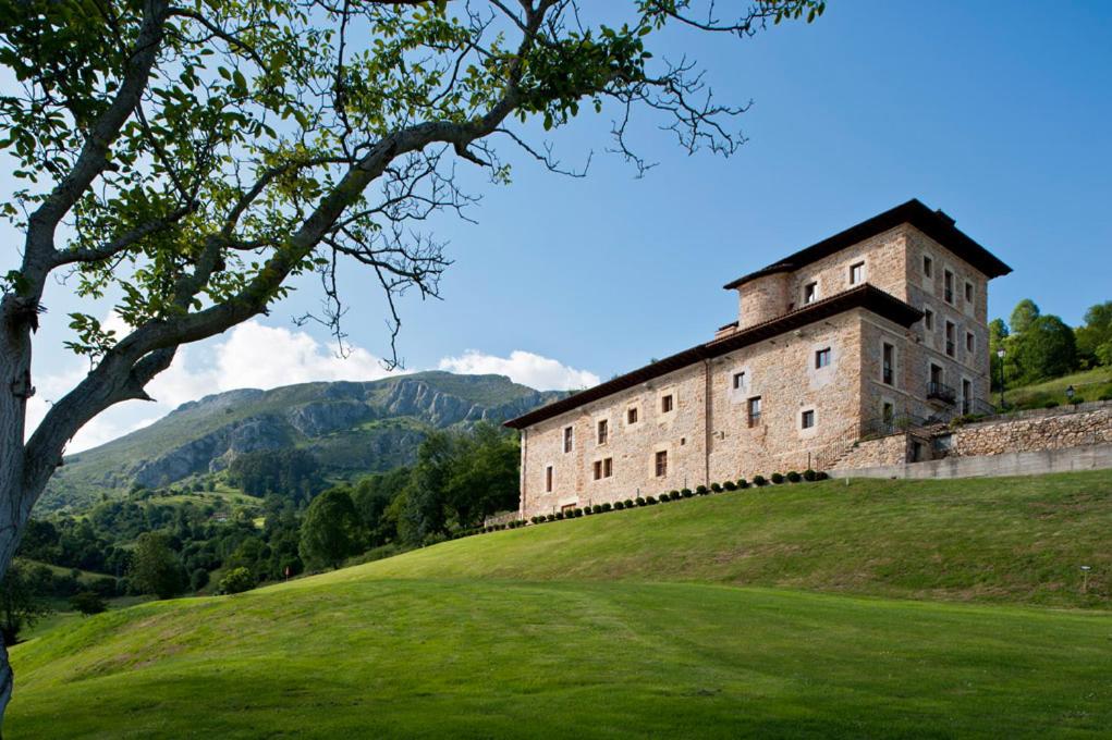 a building on top of a grassy hill with a tree at Narbasu Restaurante y Hotel in Cereceda