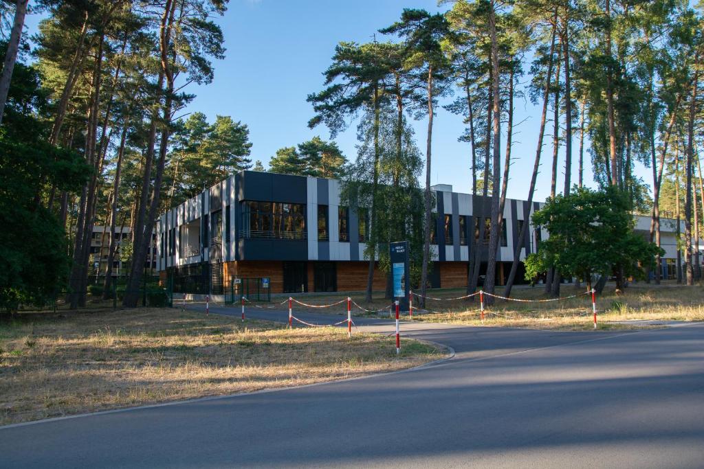 a building on the side of a road with trees at Ośrodek Wypoczynkowy Wielki Błękit in Łukęcin
