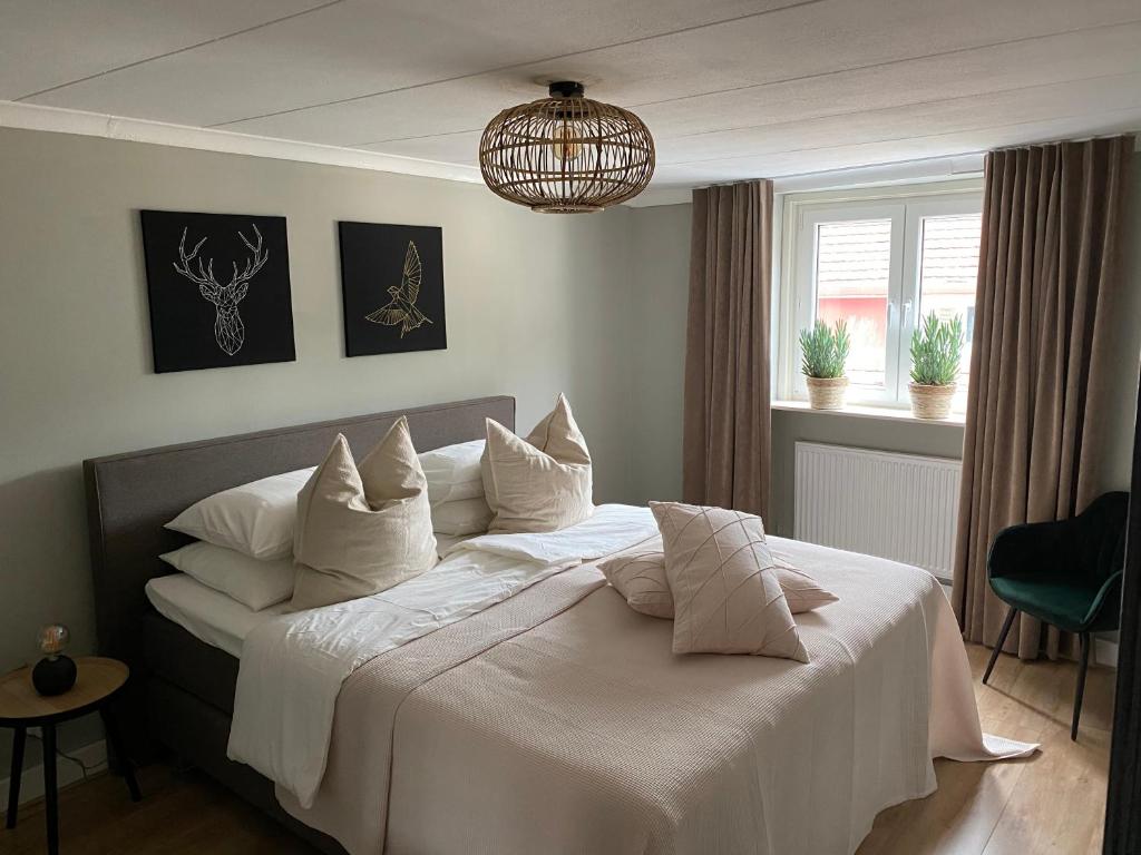 een slaapkamer met een groot bed met witte lakens en kussens bij Appartement Charmaux Valkenburg in Valkenburg