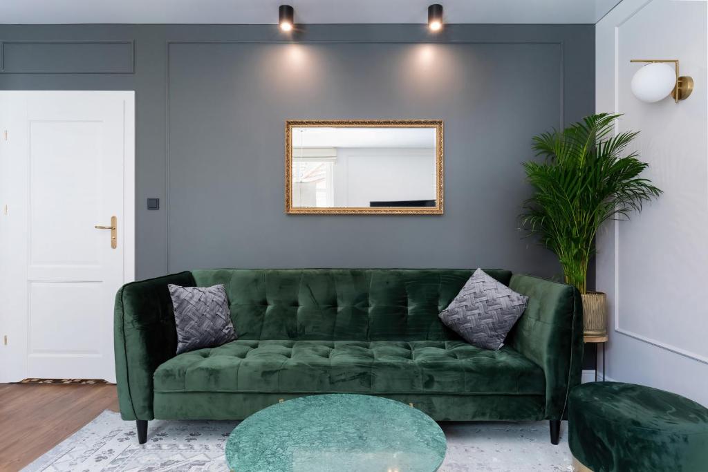 a green couch in a living room with a mirror at Apartament Premium na Rynku by Renters Prestige in Darłowo