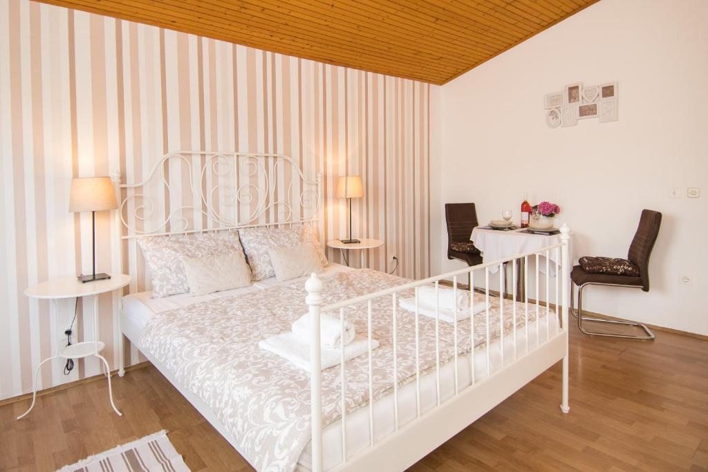a white bedroom with a white bed and two chairs at Apartments & Rooms Darrer in Poreč