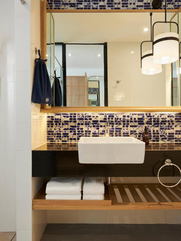 A compact vanity area features a vessel sink, tiled backsplash and open towel storage.