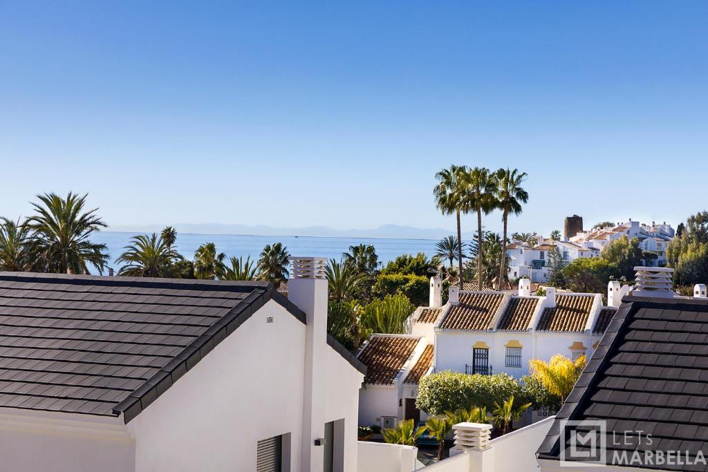 a view of the roofs of houses and the ocean at Estepona Sunsets - Modern 3-BR Beachside Apartment in Estepona