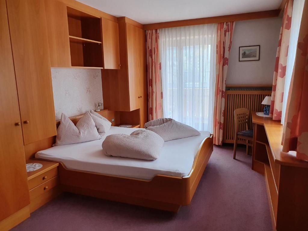 a bedroom with a bed with white sheets and a window at Gasthof Mooserwirt - Passeiertal in Moso