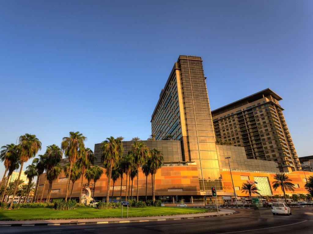 a large building with palm trees in front of it at Swissôtel Al Ghurair Dubai in Dubai