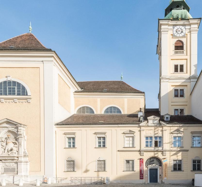 un grand bâtiment avec une tour d'horloge en haut dans l'établissement Benediktushaus im Schottenstift, à Vienne