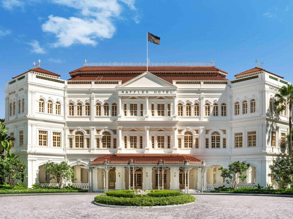 a large white building with a flag on top at Raffles Singapore in Singapore