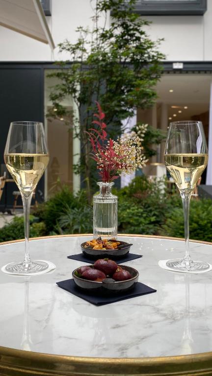 two glasses of wine and a plate of food on a table at Maison Albar - Le Vendome in Paris