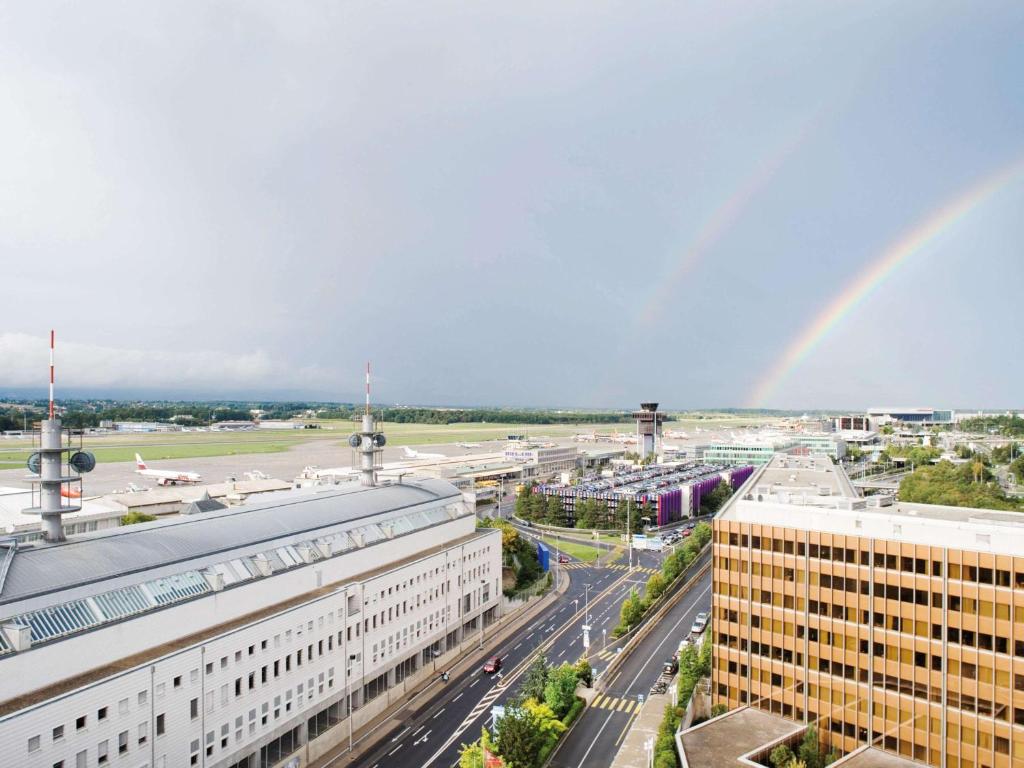 a city with a rainbow in the sky at Mövenpick Hotel & Casino Geneva in Geneva