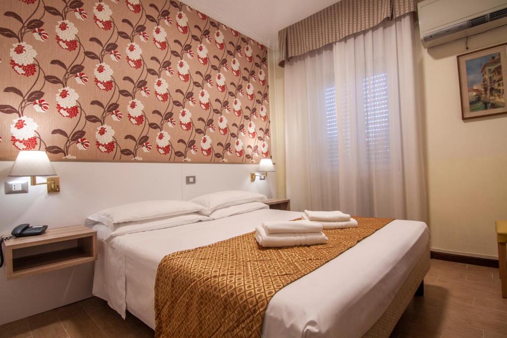 a bedroom with two beds and a floral wall at Hotel Dei Fiori in Milan