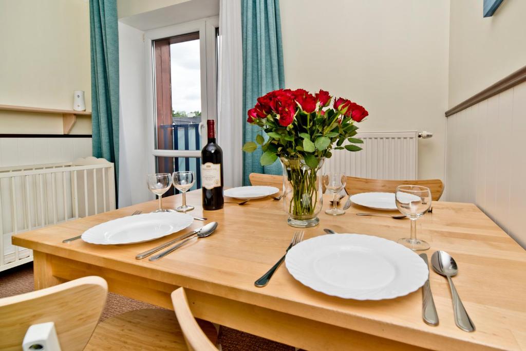 une table en bois avec des assiettes et un vase de fleurs dans l'établissement Apartamenty.in Villa Baltic, à Chałupy