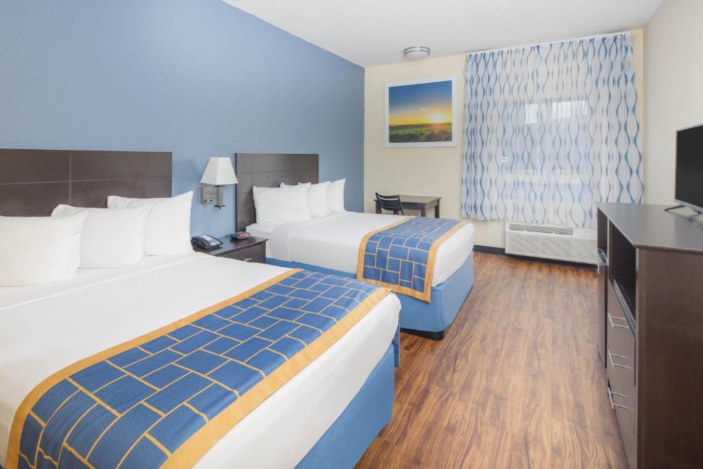 a hotel room with two beds and a flat screen tv at Days Inn by Wyndham Macon I-75 North in Macon