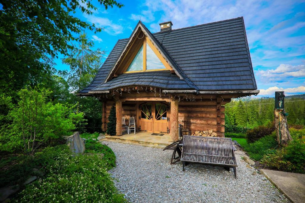 uma cabana de madeira com um banco à frente em Alpejska Szarotka em Nowe Bystre