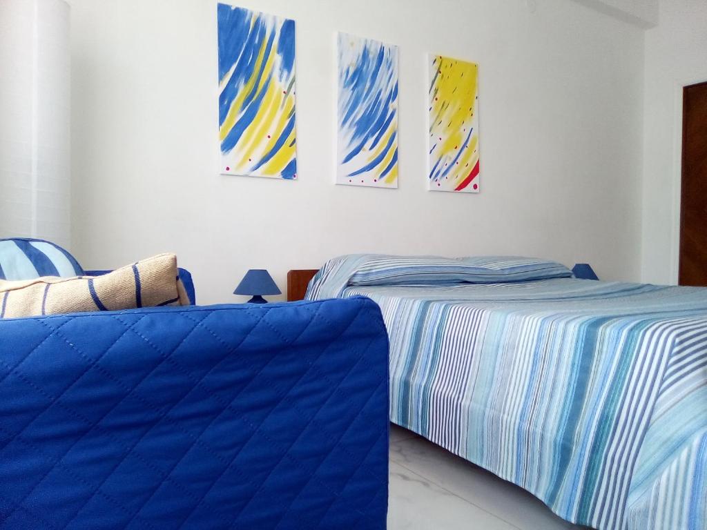 a bedroom with two beds and paintings on the wall at Atmosfera B&B al centro della città in Cosenza