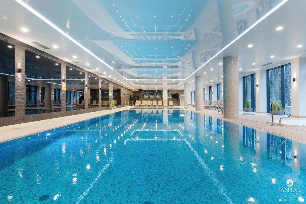 duży basen z niebieską wodą w budynku w obiekcie Jantar Apartamenty - Nadmorskie Tarasy SPA 2 w Kołobrzegu