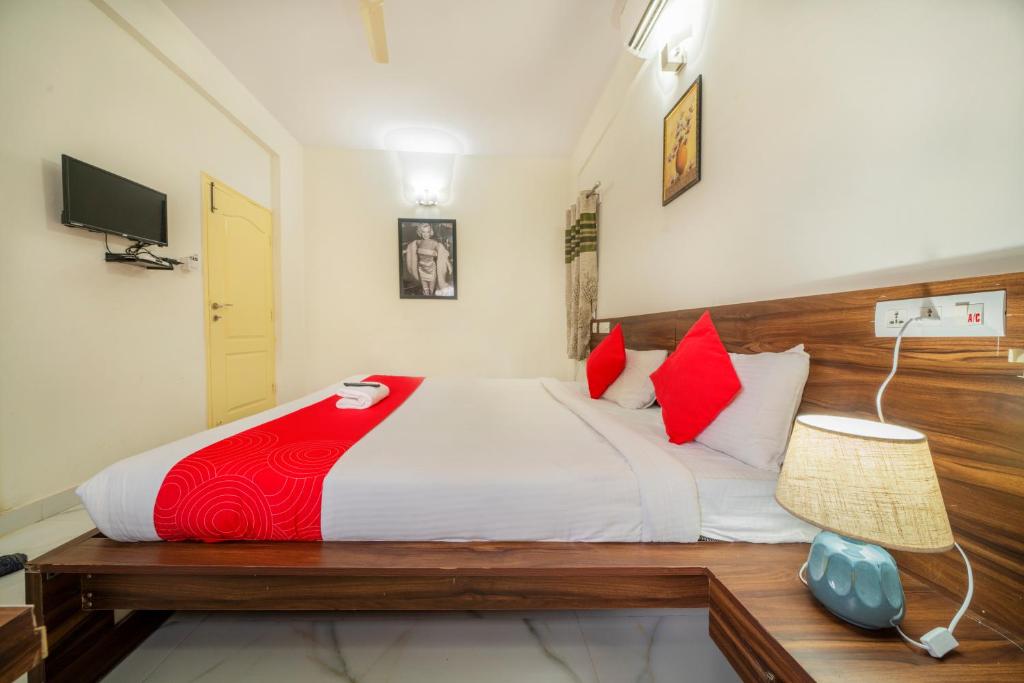 1 dormitorio con 1 cama grande con almohadas rojas en Sports Icon Suites, en Yelahanka