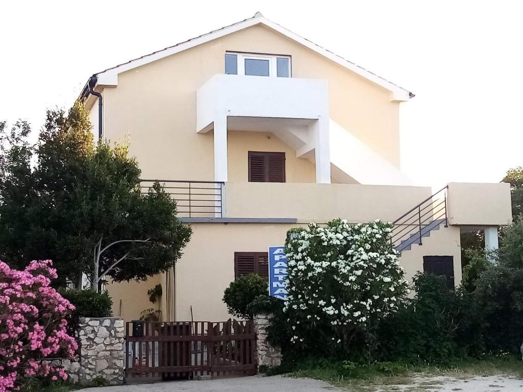 uma casa branca com uma cerca e flores em Apartments Božito em Nin